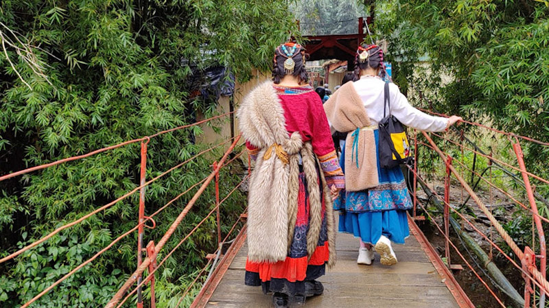 Các cô gái trong bộ trang phục Mông Cổ cẩn thận bước đi trên cây cầu treo