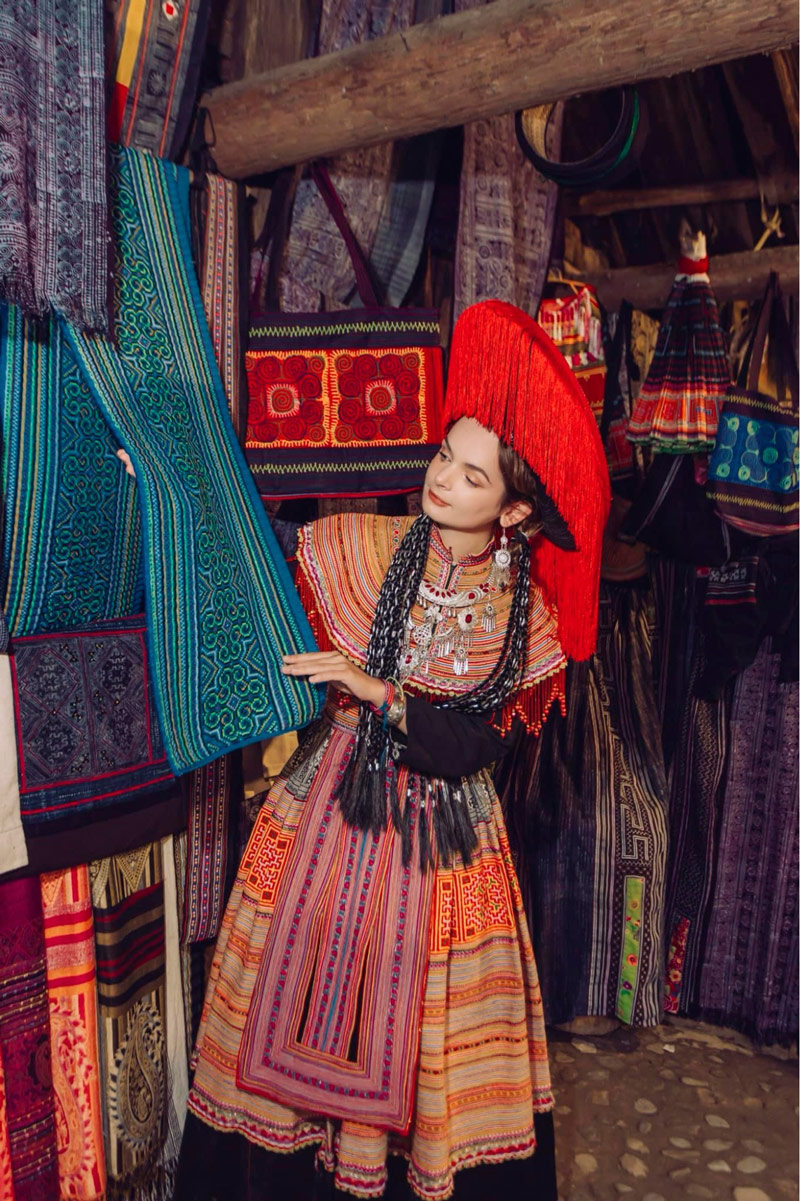 Nữ du khách nước ngoài trong trang phục truyền thống đang nâng niu tấm vải thổ cẩm